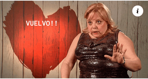 a woman stands in front of a heart with the words vuelvo written above her