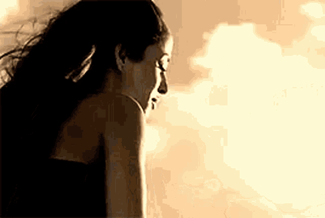 a woman is standing in front of a cloudy sky looking down .