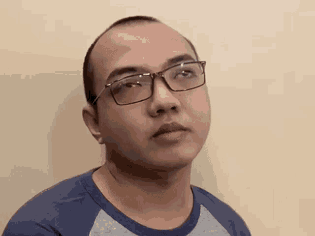 the man is wearing glasses and a blue shirt .
