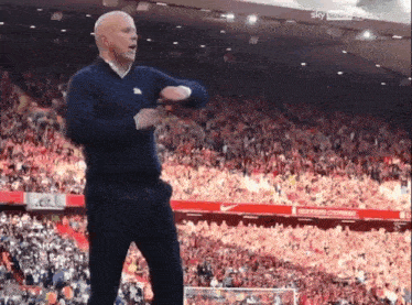 a man stands in front of a crowd in a stadium that says sky sports on the bottom