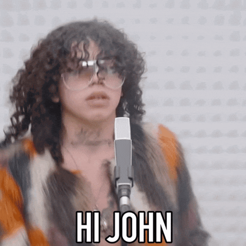 a woman with curly hair is singing into a microphone and the words hi john are above her