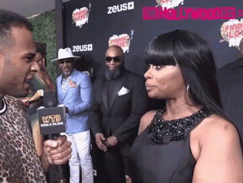a woman in a black dress is being interviewed by a man with a microphone that says wtb on it