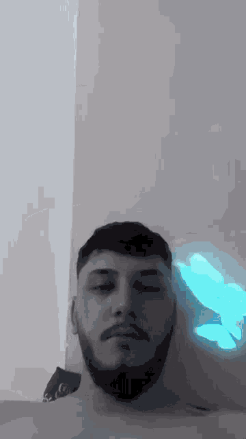 a man with a beard is looking at the camera in a black and white photo with a blue light behind him .