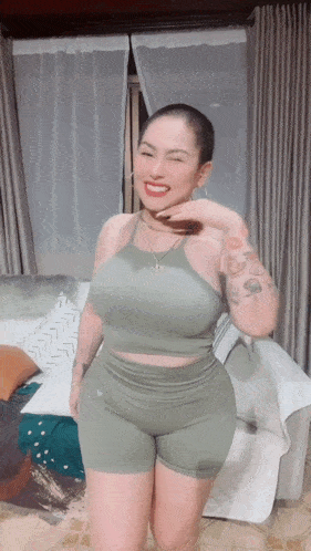 a woman with a shaved head and tattoos is wearing a green top and shorts .