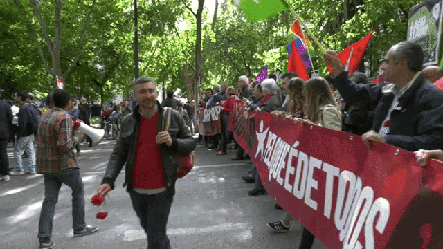 a group of people holding a banner that says " me que de todos " on it
