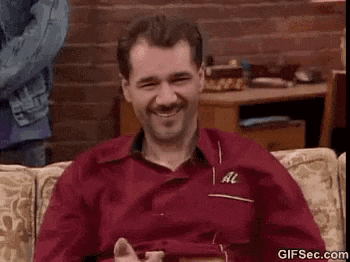 a man is sitting on a couch and giving a thumbs up .
