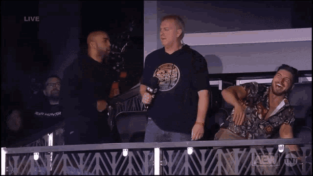 a man wearing a shirt that says aew is laughing