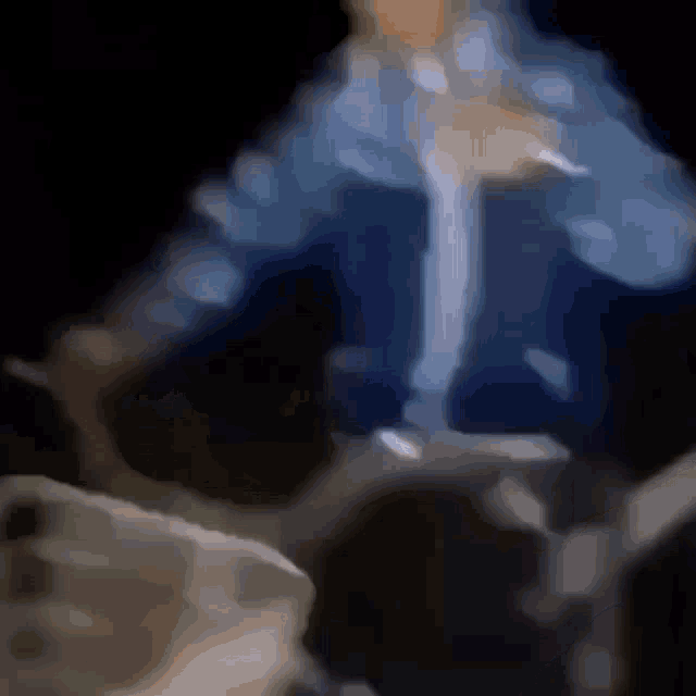 a blurry picture of a person in a blue shirt standing in the dark .