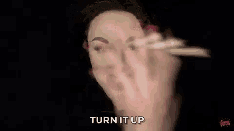 a woman with makeup on her face is holding a pair of scissors in front of her face .