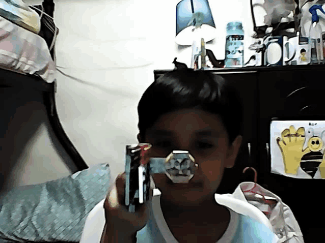 a young boy is holding a toy gun in front of a picture of a bee