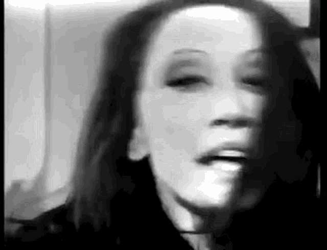 a black and white photo of a woman making a funny face with her mouth open .