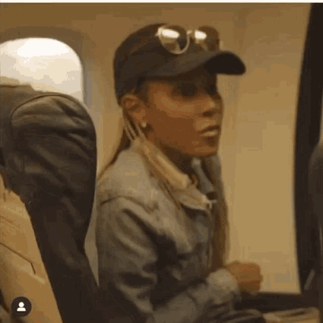 a woman wearing sunglasses and a hat is sitting on a plane