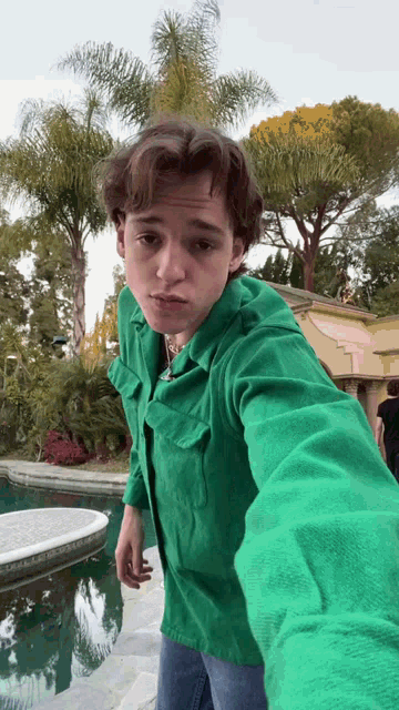 a young man in a green shirt taking a selfie