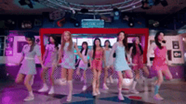 a group of girls are dancing in a room with purple lights .