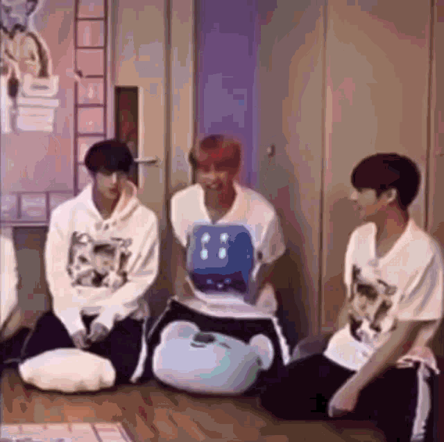 a group of young men are sitting on the floor in a room with a stuffed animal .