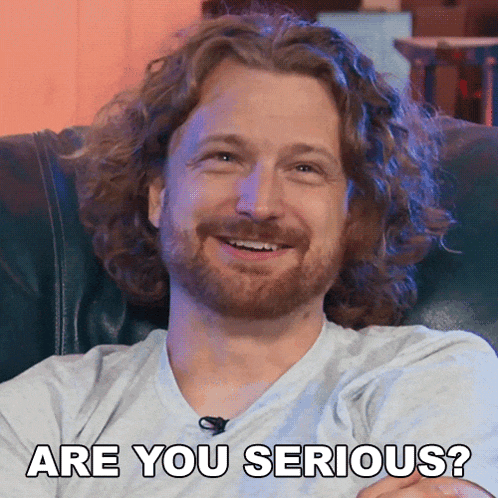 a man with curly hair and a beard is smiling and says are you serious