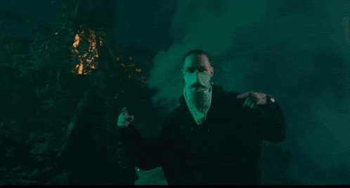 a man with a mask on his face is standing in a foggy room