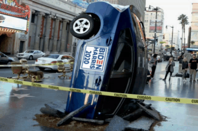 a blue car has a biden harris 2020 sign on the side of it