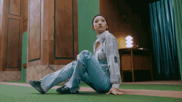 a woman is sitting on the floor wearing jeans and a newspaper shirt
