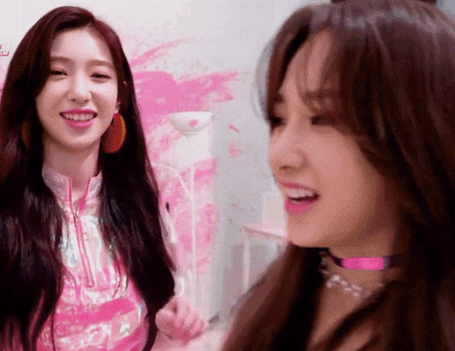 two girls are smiling and looking at each other
