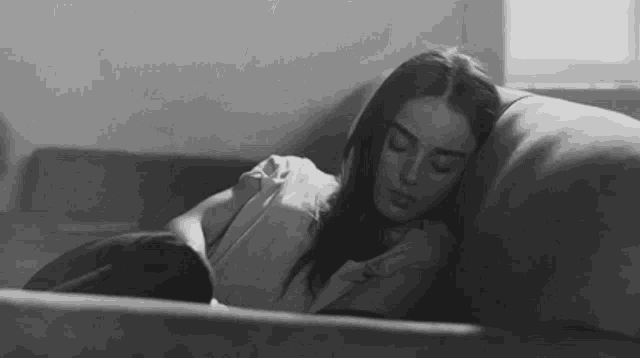 a woman is laying on a couch with her eyes closed .