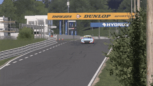 a race car is driving down a race track with a dunlop sign in the background
