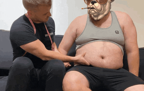 a man is measuring another man 's stomach while wearing a bulldog mask