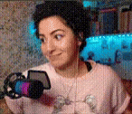 a woman wearing headphones and a pink sweater is holding a camera .