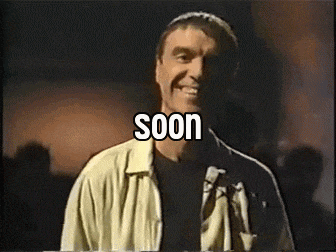 a man is smiling in front of a sign that says soon on it