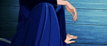 a woman in a blue skirt sits on a wooden floor with her hands on her knees