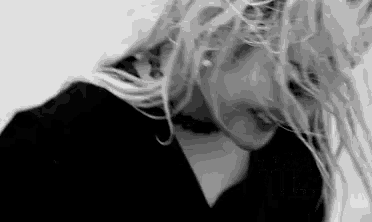 a black and white photo of a woman with long blonde hair wearing a choker .
