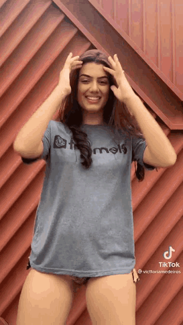 a woman wearing a t-shirt that says animals is standing in front of a red wall
