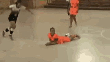 a girl in an orange dress is laying on the floor while playing soccer .