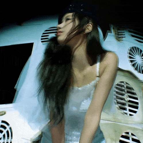 a woman with long hair is sitting in front of a stack of fans