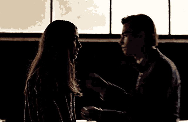 a man and a woman looking at each other in the dark