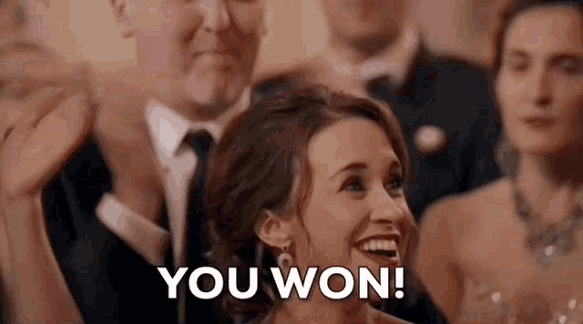 a woman in a wedding dress is laughing and saying `` you won '' while sitting in a crowd .