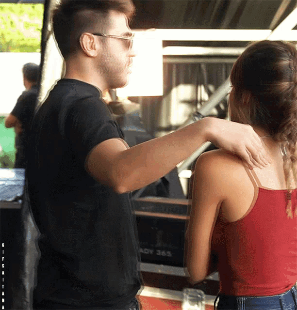 a man holds a woman 's shoulders in front of a sign that says ready 365