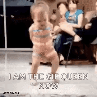 a little girl is dancing in front of a group of people while a woman holds a baby .