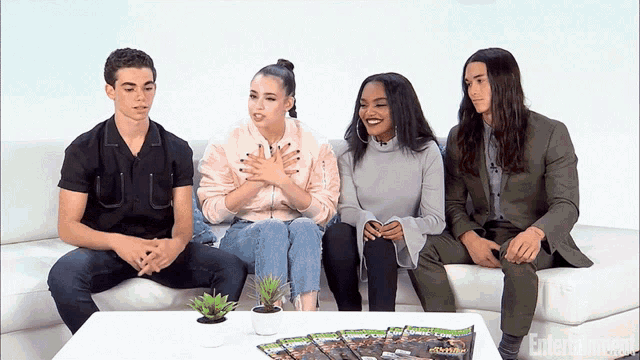 a group of people sit on a couch in front of a table with entertainment magazine on it