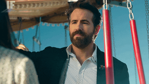 a man with a beard is standing in front of a carousel with the word if on the bottom right