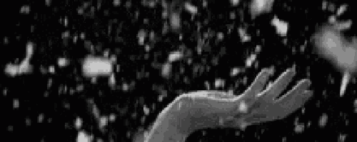 it is a black and white photo of a person 's hand reaching out towards the snow .