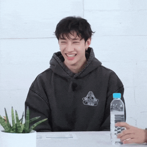 a man wearing a hoodie that says palace is smiling while sitting at a table