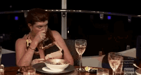 a woman is sitting at a table with a bowl of soup .