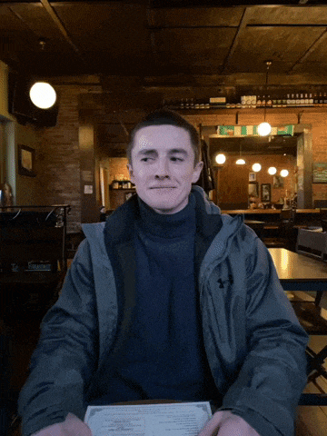 a man in an under armour jacket sits at a table with a menu in front of him