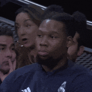 a man with a beard is wearing a blue shirt with the word real on it