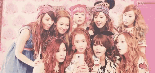 a group of young women are posing for a picture while one of them is taking a selfie .