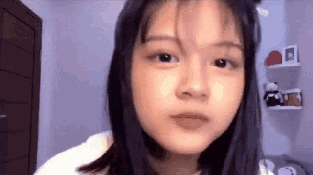 a close up of a girl 's face with a purple wall behind her