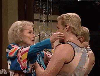 a woman is touching a man 's face in front of a nbc sign