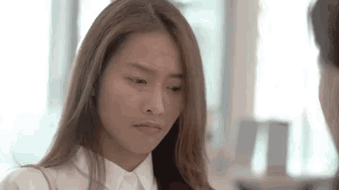 a woman in a white shirt is making a funny face while looking at the camera .