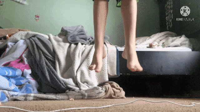 a person 's feet are hanging over a bed with a kine logo visible